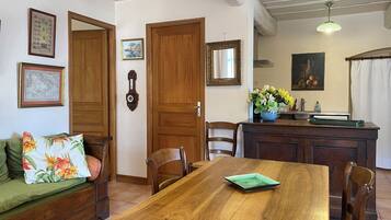 A dining area with a wooden table, chairs, a sofa, and a kitchen area with a sink and counter.