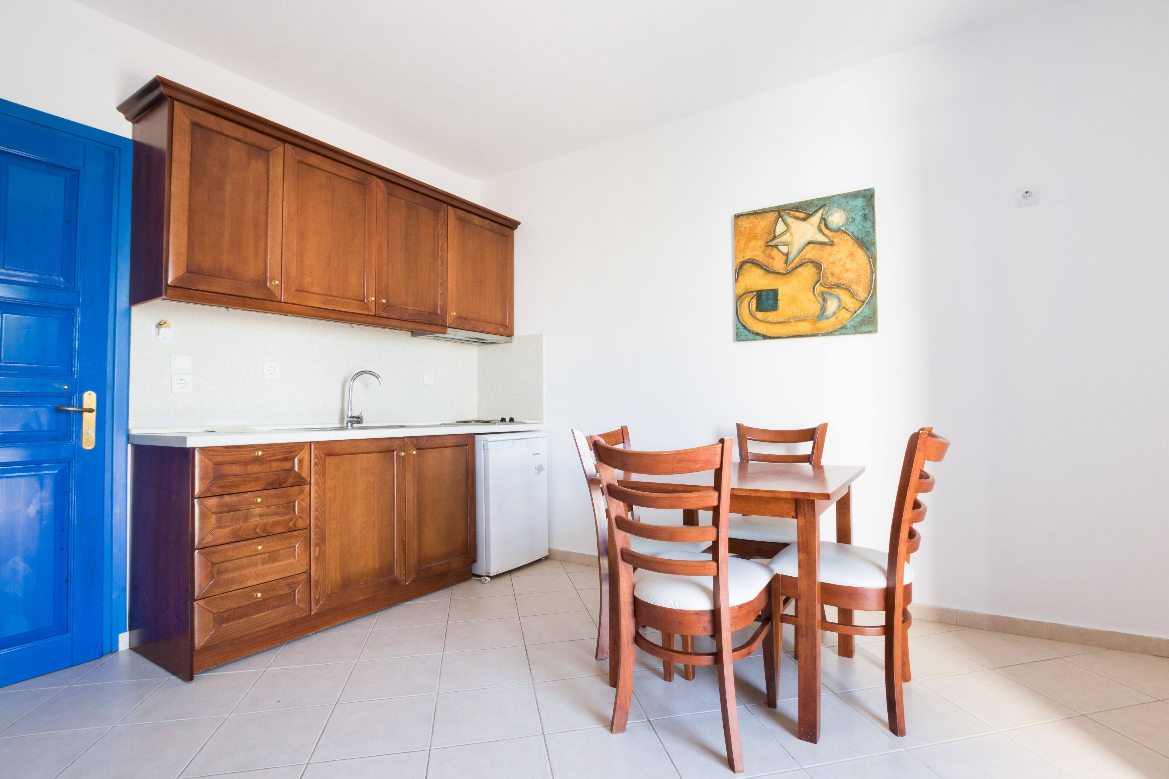 A kitchen with wooden cabinets, a white countertop, a sink, and a dining table with chairs.