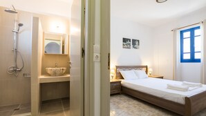 A hotel room with a shower, sink, and bed. - Summer Breeze (Karpathos)