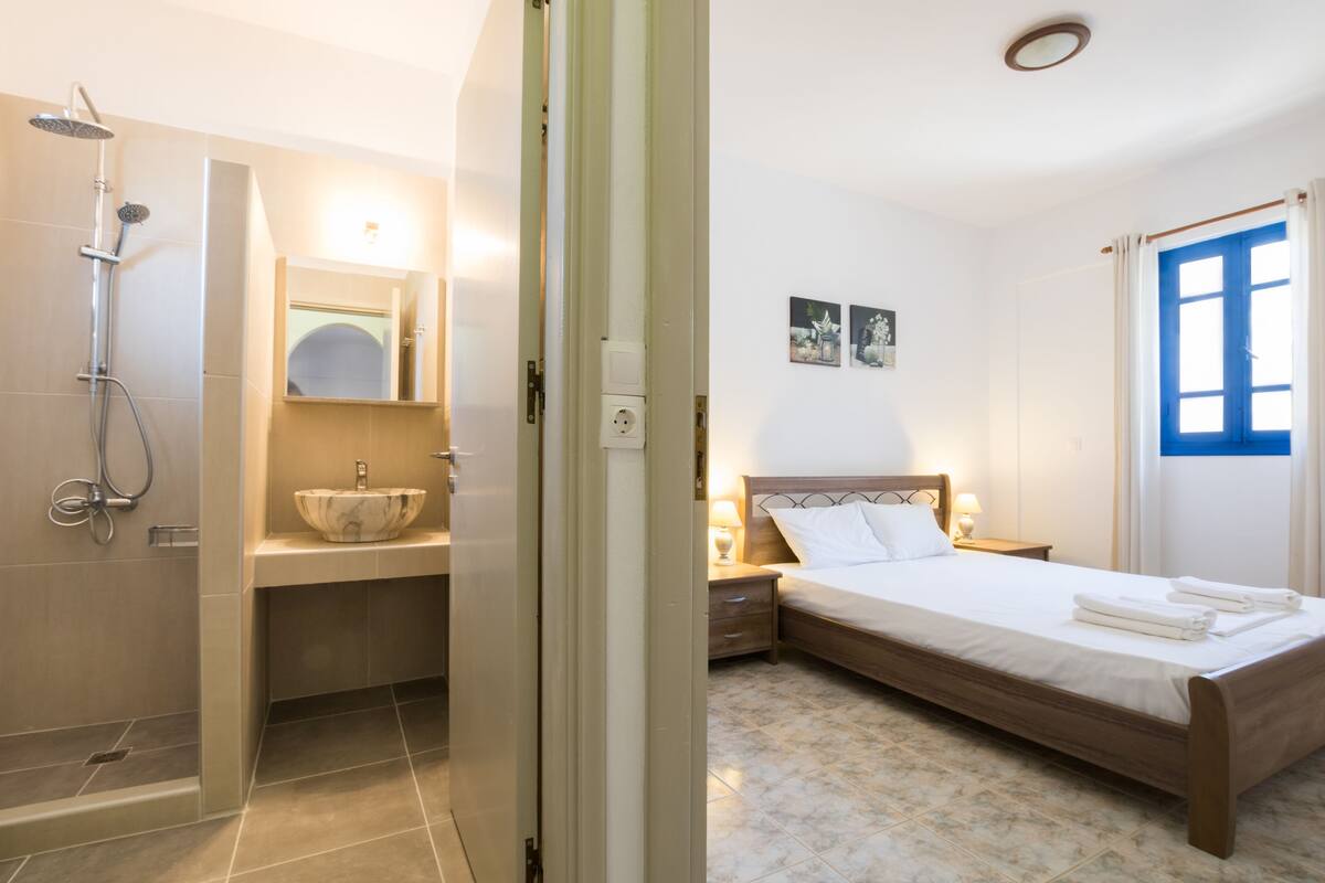 A hotel room with a shower, sink, and bed.