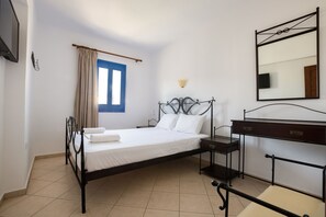A bedroom with a bed, bedside table, dresser, and a mirror. - Summer Breeze (Karpathos)