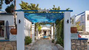 A stone pathway leading to a white building with a blue pergola entrance. - Summer Breeze (Karpathos)