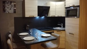Cocina compacta con comedor, equipada con estufa, horno, pileta y microondas.