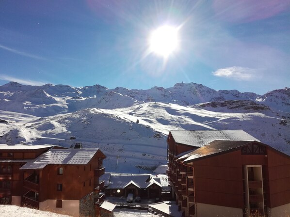 A snow-covered mountain village with wooden buildings and a clear view of the mountains.