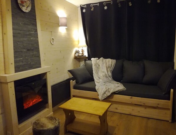 Una sala de estar acogedora con chimenea, un sofá y una pequeña mesa de madera.