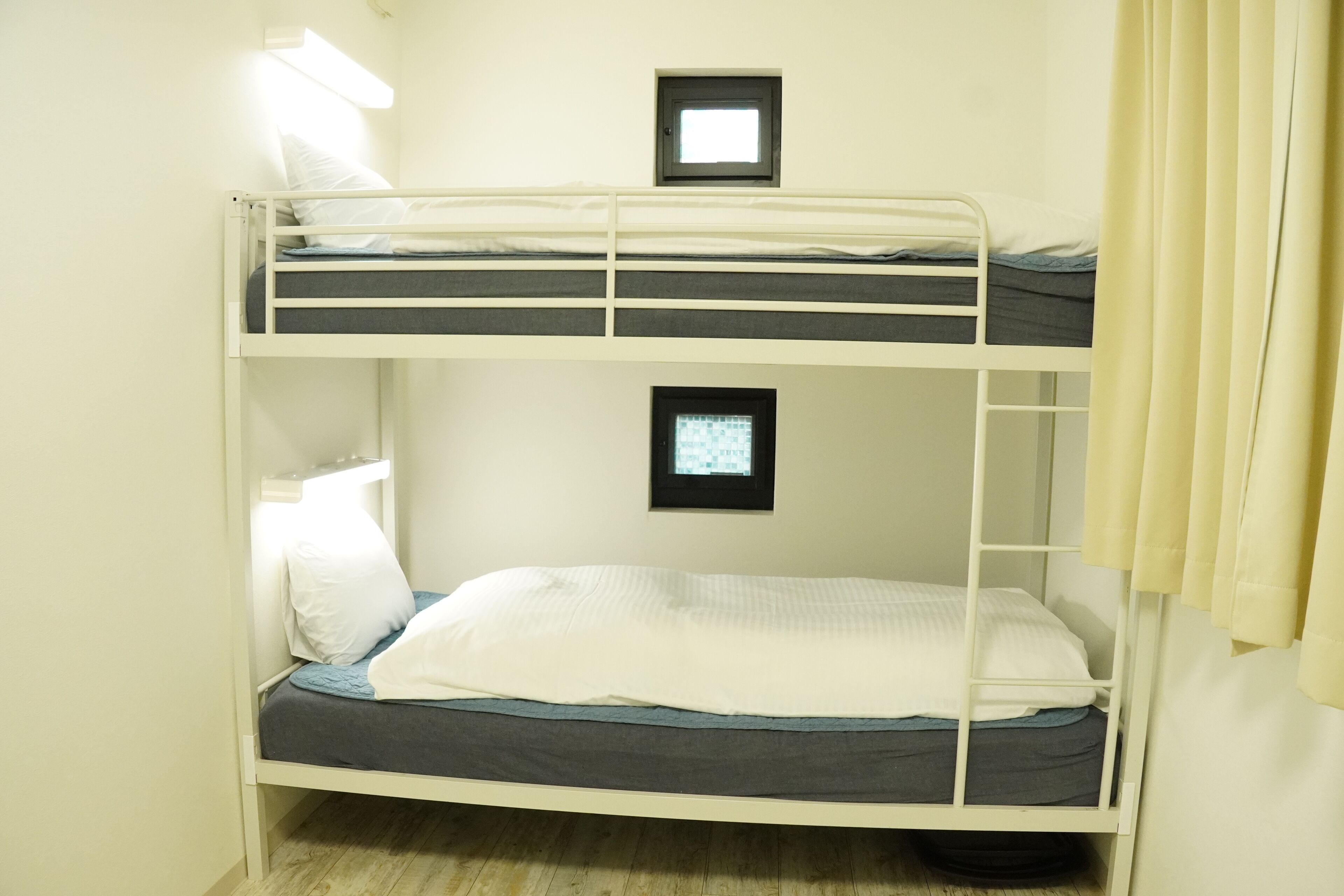 A bunk bed room with two beds, a small window, and a door.
