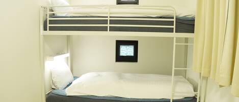 A bunk bed room with two beds, a small window, and a door.