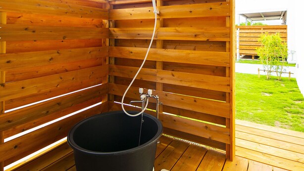 A wooden sauna with a black tub and a hose. - Painushima Resort (Ishigaki)
