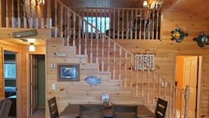 A wooden interior with a staircase, a dining area with four chairs, and a fish-themed wall decoration. - Lakeside bliss and serenity in the Northwoods (Makinen)
