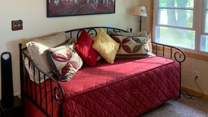 A bedroom with a bed, a painting of trees, a window with curtains, and a lamp. - Quiet, Cozy Lake Cottage North of Merrifield, Great Getaway! (Merrifield)