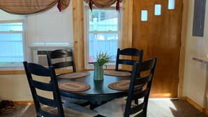 A dining area with a round table, four chairs, a vase with greenery, and a wooden door with windows. - Quiet, Cozy Lake Cottage North of Merrifield, Great Getaway! (Merrifield)