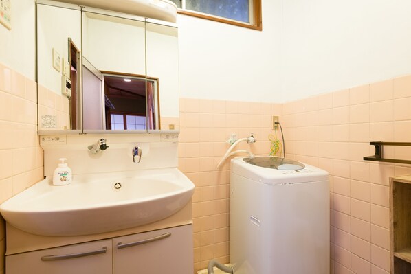 A bathroom with a sink, mirror, and a white washing machine.
