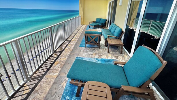A balcony with a view of the ocean, featuring a seating area with chairs and a table. - Platinum Gulf-Front Corner Unit, Million Dollar Views, Free Beach Service (Panama City Beach)