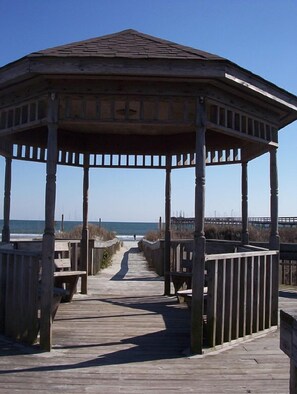 A wooden gazebo with a roof, supported by columns, on a wooden boardwalk leading to the beach. - Most Requested Unit, The Colony II Condo, free wi-fi  (Sunset Beach)