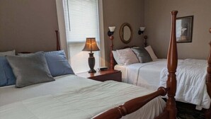 A hotel room with two single beds, a nightstand with a lamp, a mirror, and a framed picture on the wall. - Gate House (2 Doubles - 2nd Floor) (Lancaster)