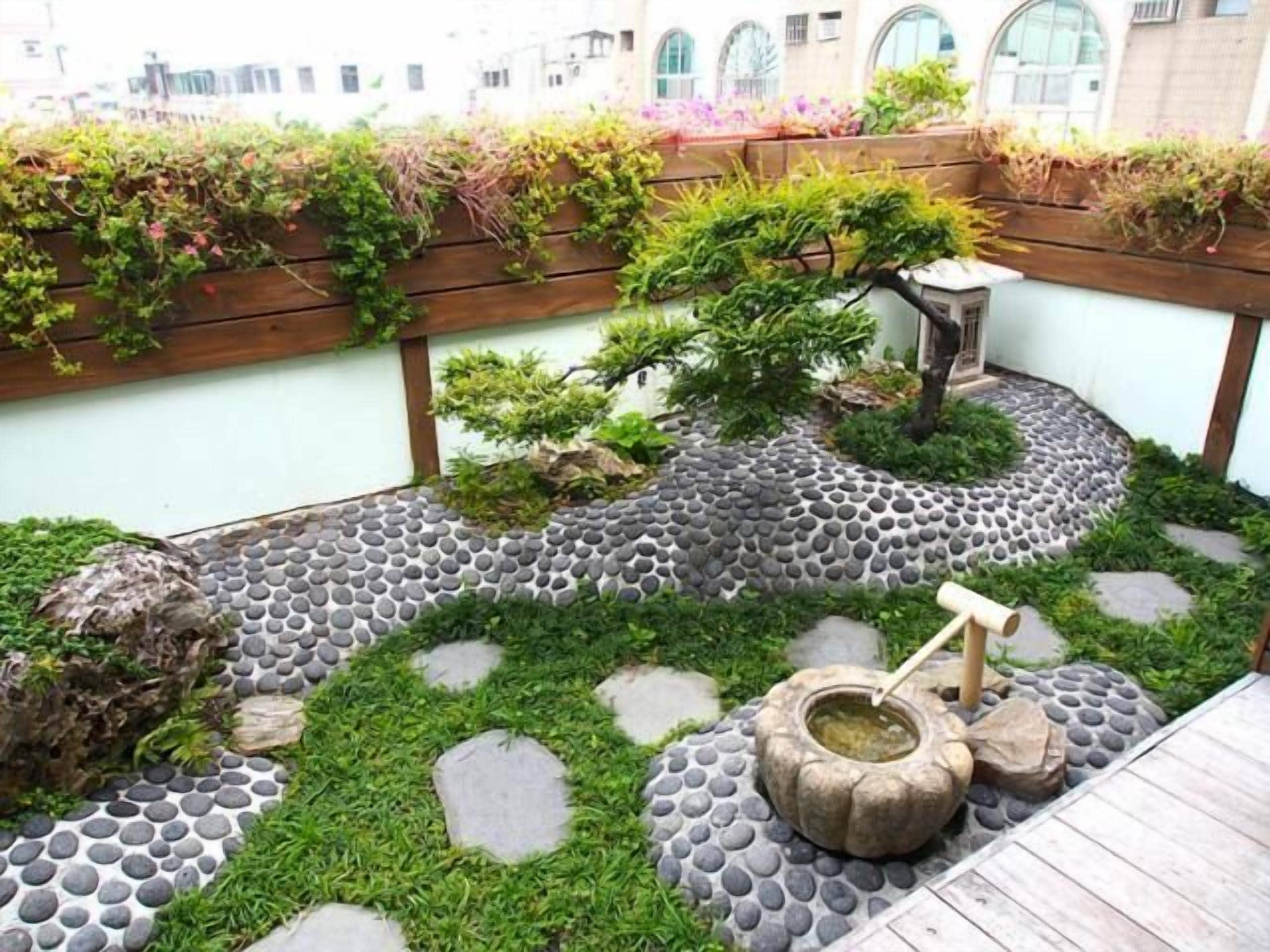 A garden with a stone pathway, a bonsai tree, and a traditional Japanese water feature.