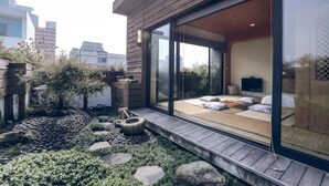 Ein modernes Gebäude mit Holzfassade und Glastür, die zu einem Zimmer mit Bett und Fernseher führt.