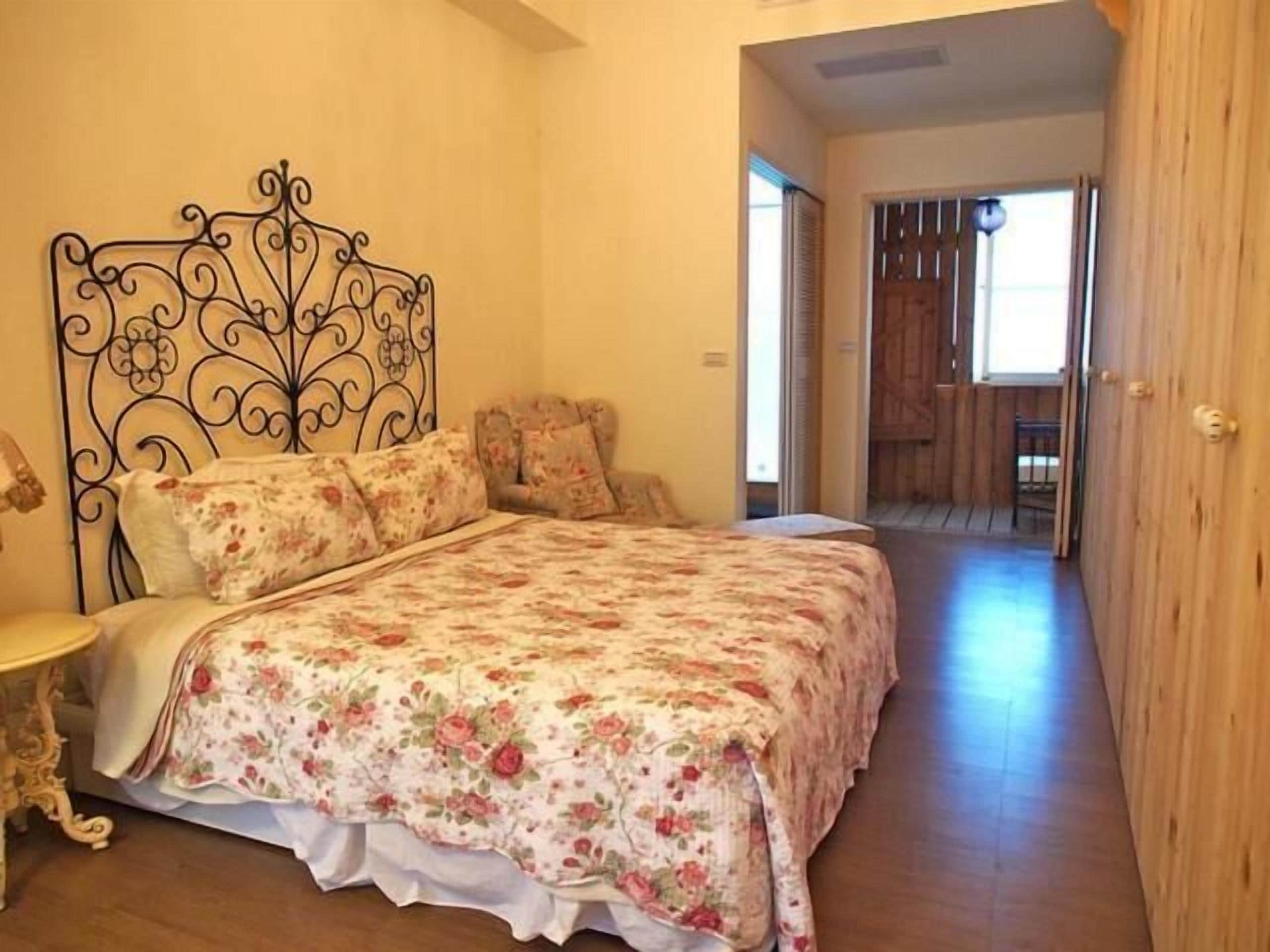 Une chambre à coucher avec une couvre-lit à motifs floraux, une tête de lit en métal et une porte en bois.