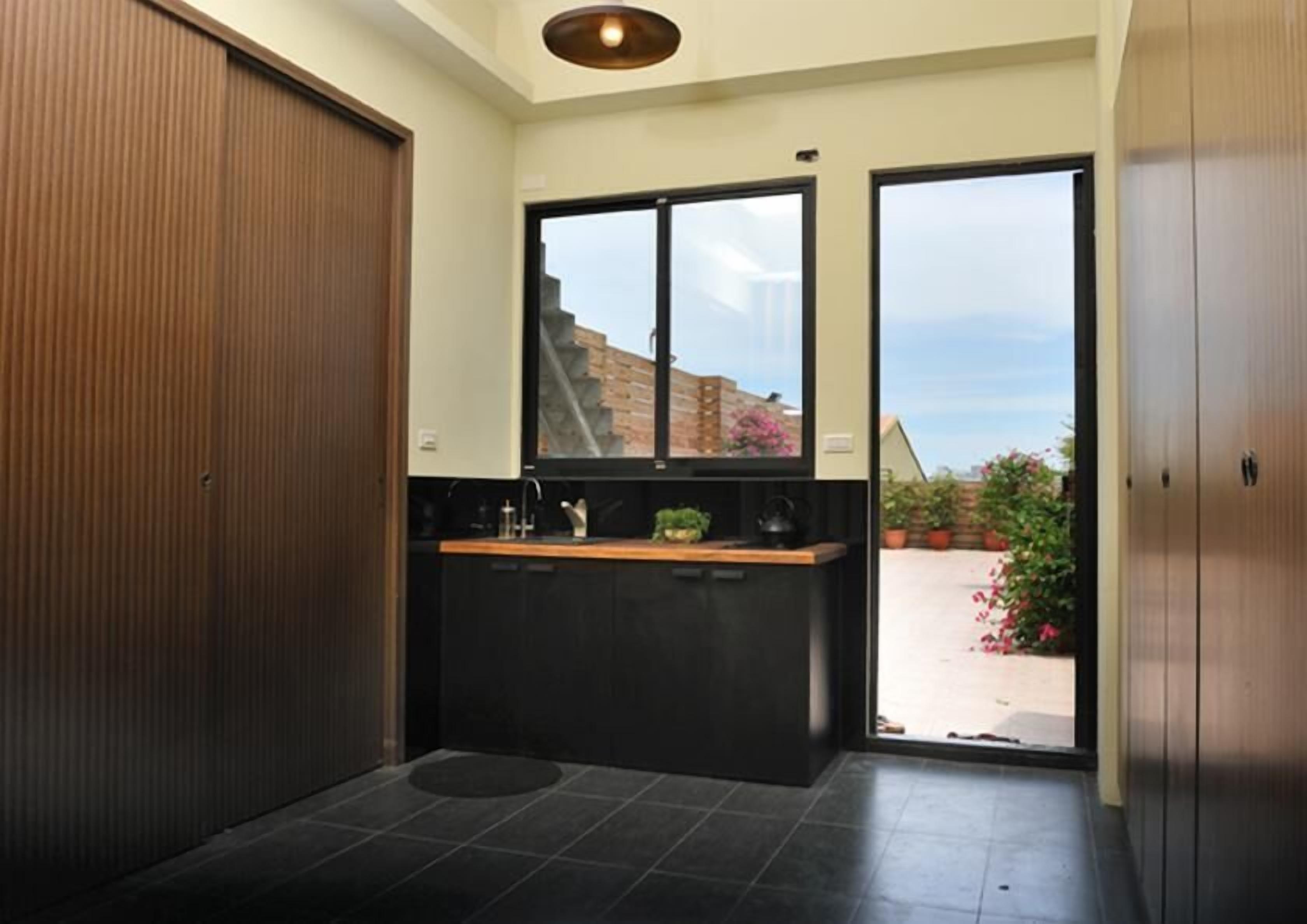 Una cocina moderna con encimera negra, un fregadero y ventana con vistas a un jardín.