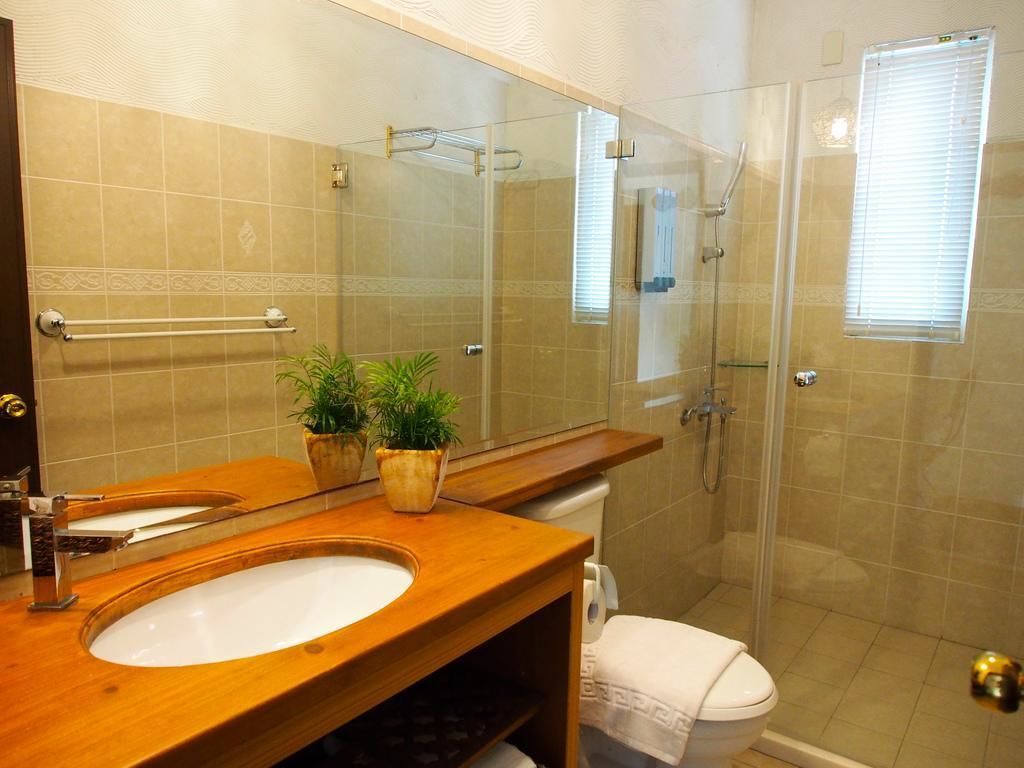 Une salle de bain avec un meuble-lavabo en bois, un évier, un miroir, un porte-serviettes, des toilettes et une douche à parois de verre.
