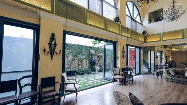 Ein geräumiges Wohnzimmer mit großem Fenster, einer Chandelüster und Blick auf einen Garten.