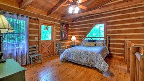 A wooden cabin bedroom with a bed, a ceiling fan, a window, and a door. - Sans Souci | Pet Friendly (Copperhill)