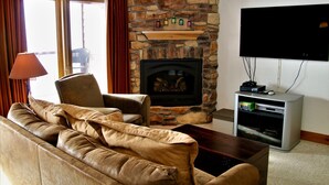 Una sala de estar con chimenea de piedra, sofá de cuero y televisor de pantalla plana.
