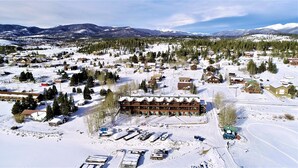 Un pueblo cubierto de nieve con un imponente alojamiento de varios pisos y un telesilla cercano.