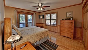 Ein Schlafzimmer mit Bett, Holzkapelle, Fernseher und Deckenventilator.