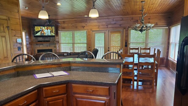 A wooden interior with a kitchen island, dining area, and built-in TV. - 4 bd cabin with gorgeous sunset view and minutes to everything.  (Gatlinburg)