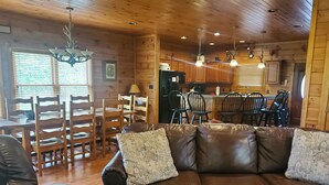 A cozy cabin interior with a leather sofa, wooden dining table, and chairs. - 4 bd cabin with gorgeous sunset view and minutes to everything.  (Gatlinburg)