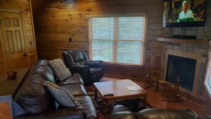 A cozy living room with a leather sofa, a recliner, and a fireplace. - 4 bd cabin with gorgeous sunset view and minutes to everything.  (Gatlinburg)
