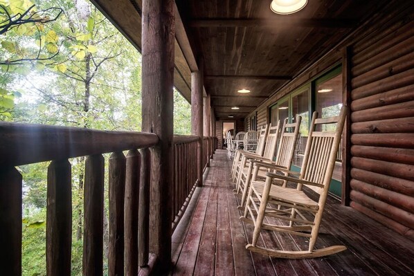 Una cabaña de madera con porche, mecedoras y vistas al bosque.