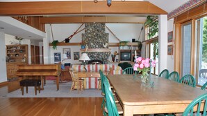 Ein geräumiger Essbereich mit einem Holztisch, Stühlen, einem Klavier und einer Steinwand.