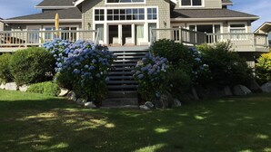 Ein zweistöckiges Haus mit einer großen Veranda, einem überdachten Eingangsbereich und einem Steinsschornstein.