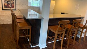 Una cocina moderna con barra, sillas de madera y un cuadro en la pared.