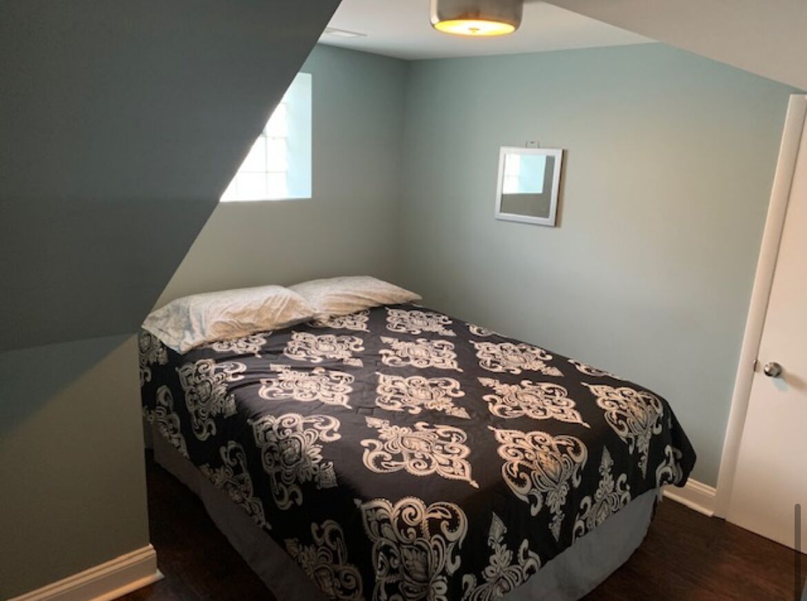 A bedroom with a bed, a window, and a door.