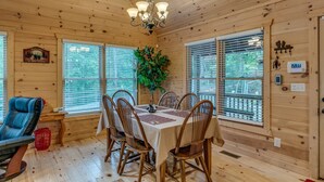 A wooden cabin interior with a dining table set for six, surrounded by wooden chairs. - Country Dreams | Near Ocoee River | Hot Tub | Fire Pit (Copperhill)