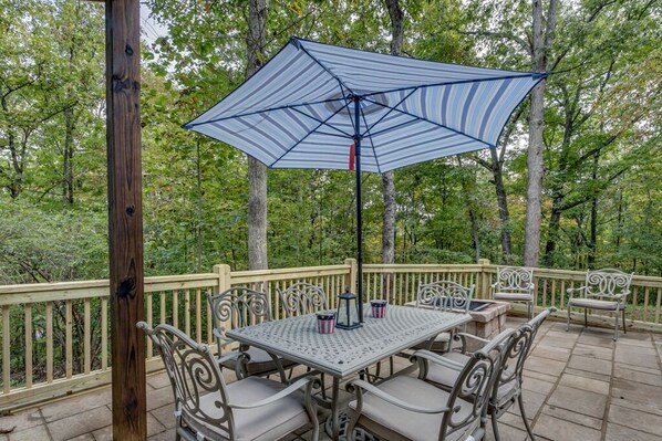 Eine überdachte Terrasse mit Tisch und Stühlen, umgeben von einer Holzterrasse und Bäumen.