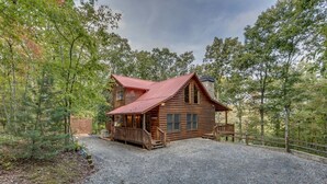 A rustic log cabin with a gravel driveway, surrounded by trees. - Country Dreams | Near Ocoee River | Hot Tub | Fire Pit (Copperhill)