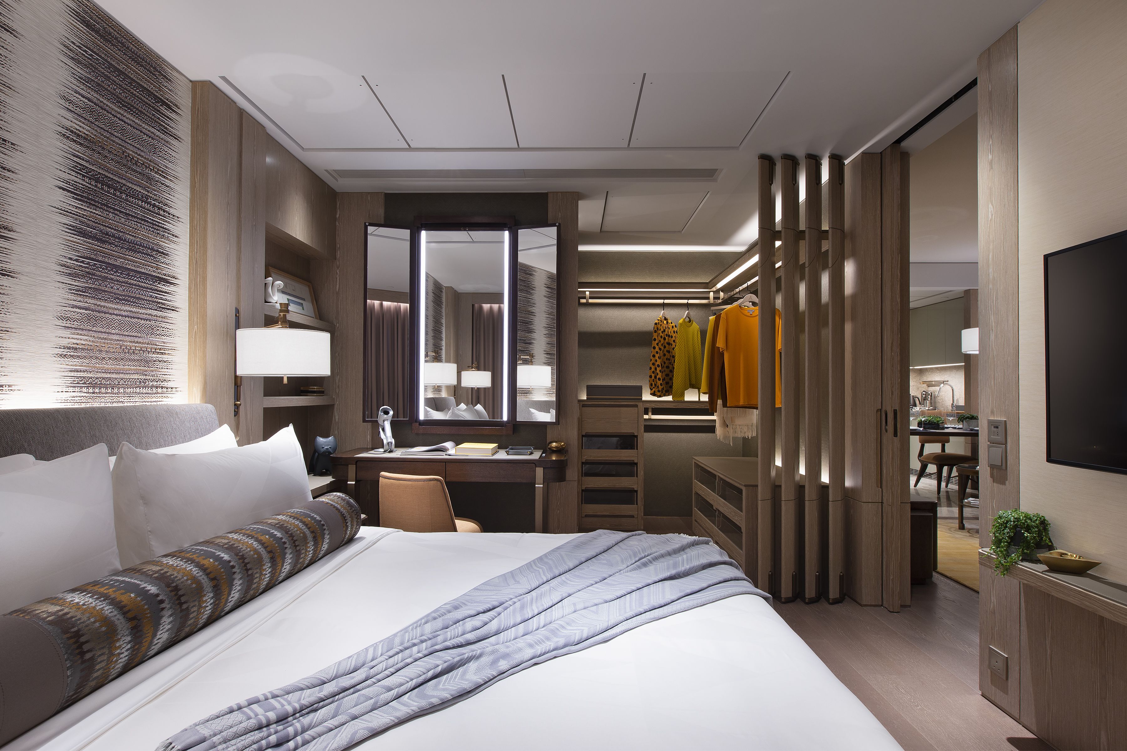 A modern hotel room with a large bed, a desk, and a wardrobe.