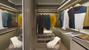 A walk-in closet with hanging clothes, a mirror, and a table with a magazine.