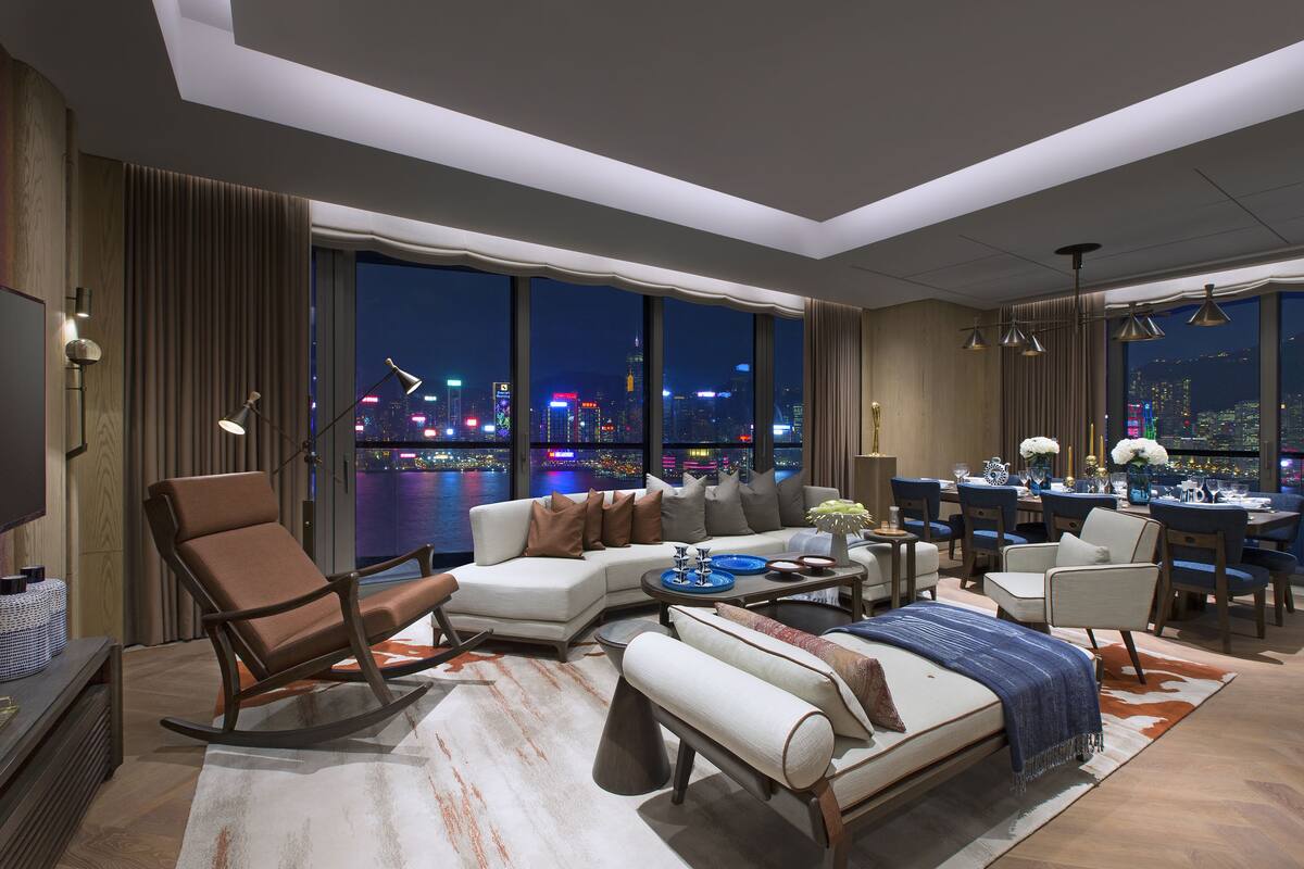 A modern hotel room with a large city view, a sofa, a dining area, and a bed.