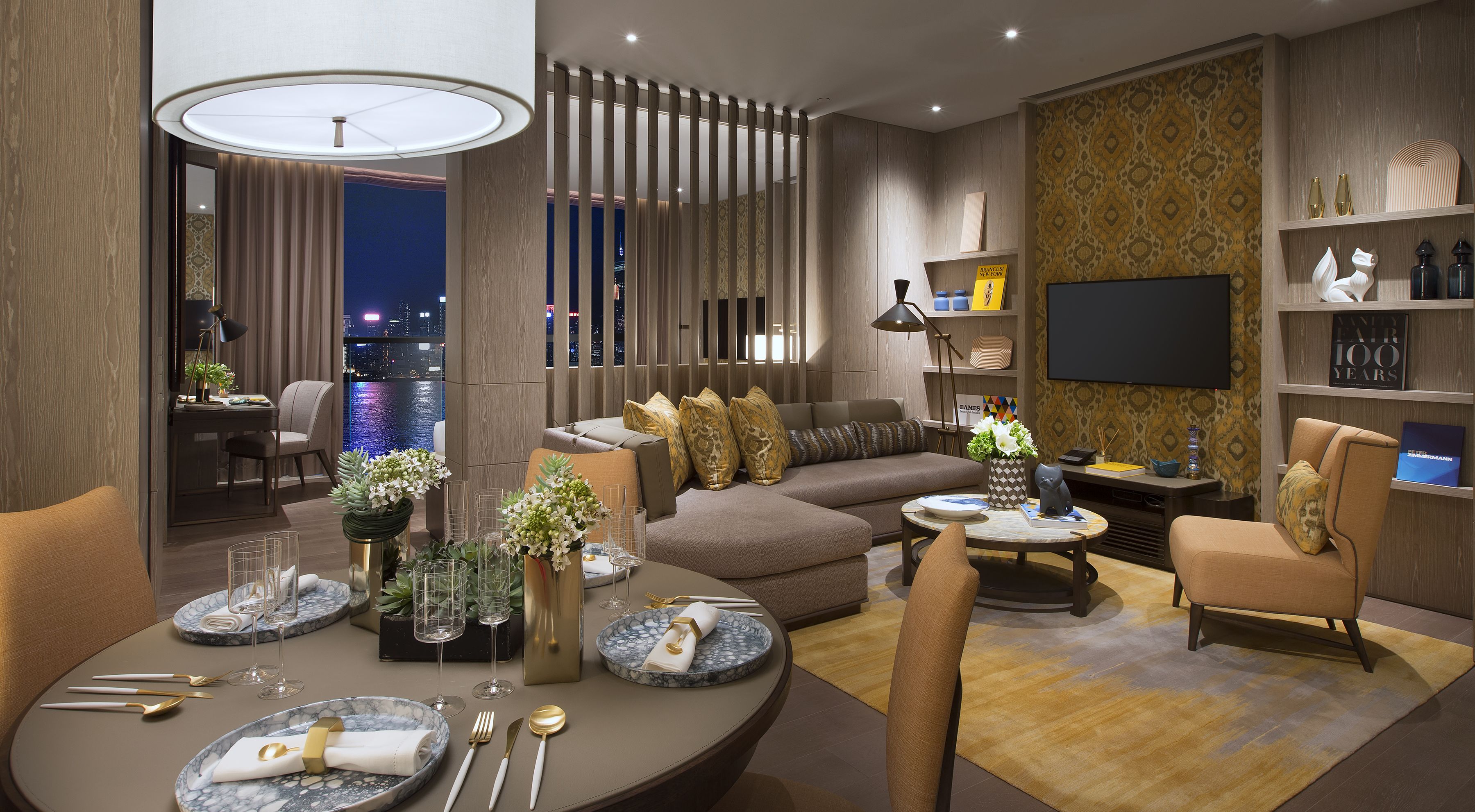 A modern living room with a sofa, chairs, a dining table set with plates and cutlery, a TV, and a bookshelf.