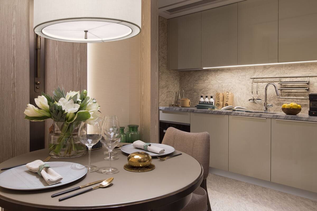 A dining table set with plates, cutlery, and a vase of flowers.