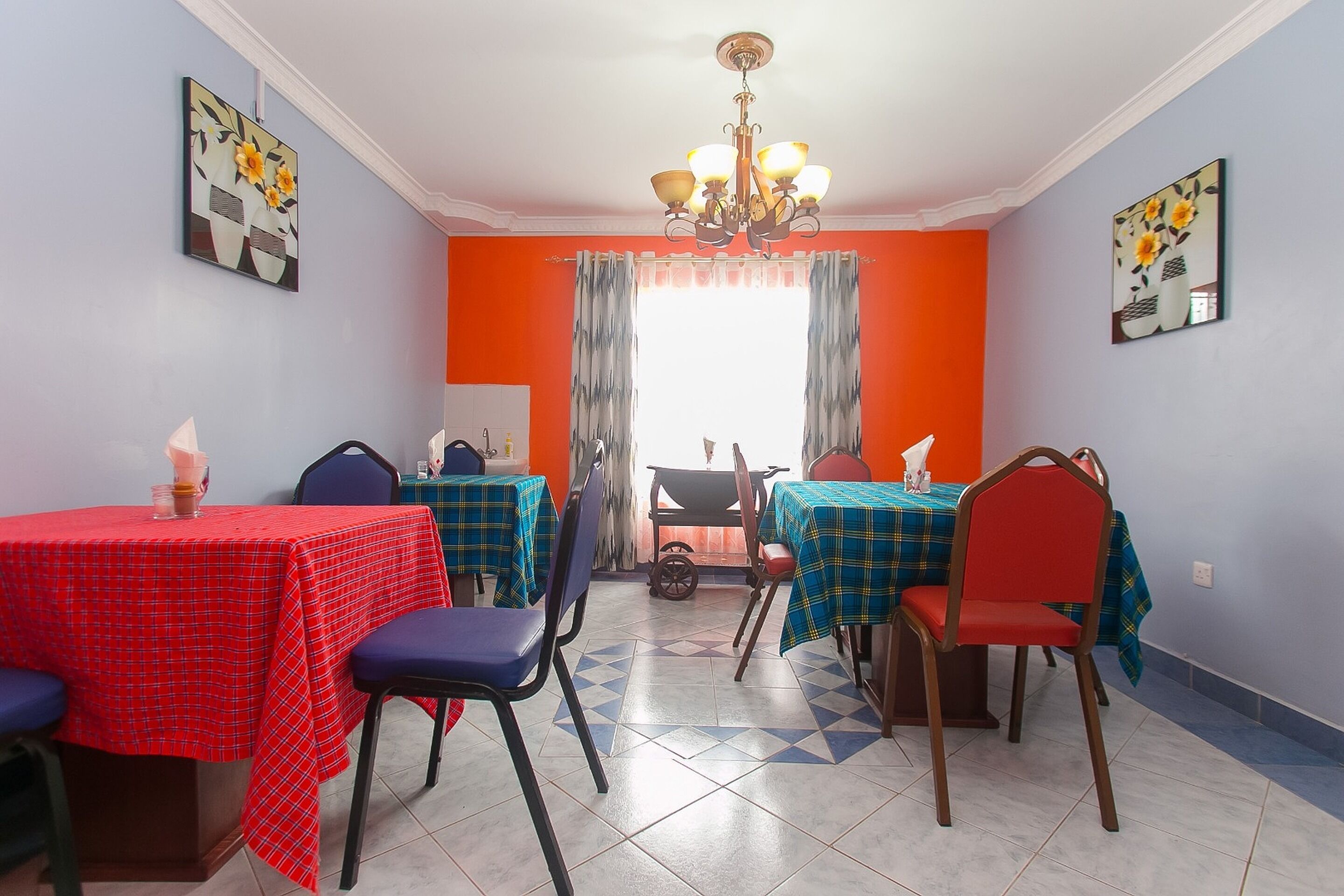 Un comedor con mesas y sillas, una araña y obras de arte en las paredes.