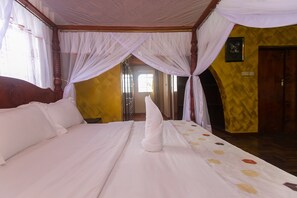 Cozy retreat with a large bed, wooden headboard, and sheer drapes.