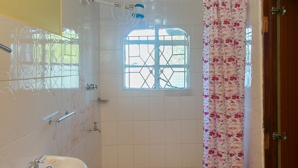 Une salle de bain avec une douche, un lavabo et une fenêtre.