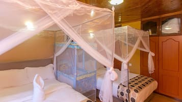 Un dormitorio con dos camas, una con dosel y la otra con colcha de lunares. Hay un armario con espejo y una mesita de noche junto a las camas.