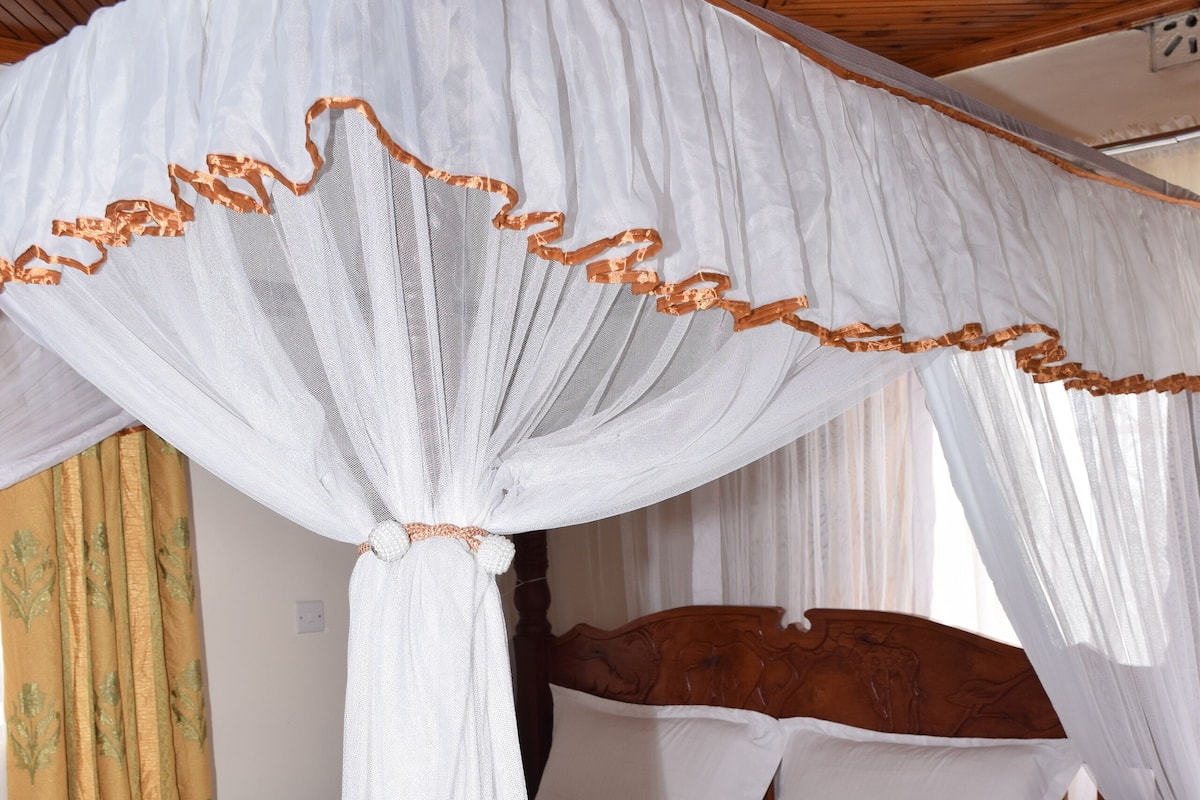 Una cama con dosel, cabecera de madera y un sofá gris.